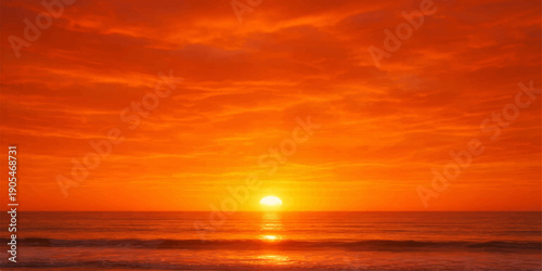 A beautiful orange sunset reflects over the calm ocean waves as the sun meets the horizon under a glowing summer sky