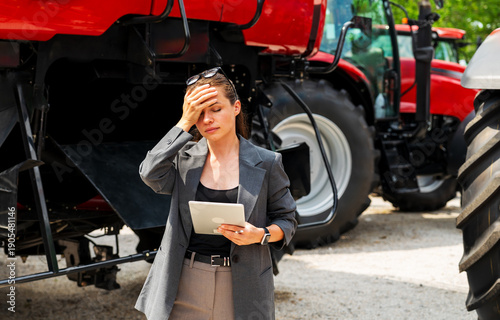 Photos Tired businesswoman in agribusiness under stress standing by heavy machinery
