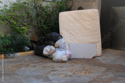 Tableau sur toile A discarded mattress rests against concrete wall near garbage room