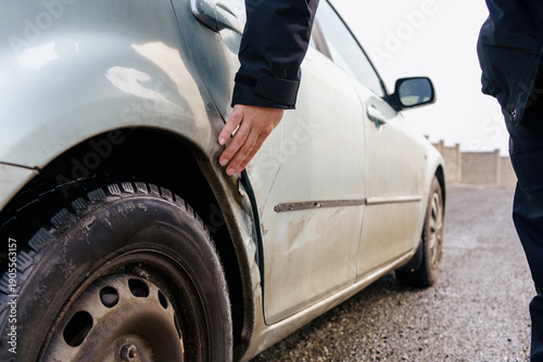 Foto Person examining damage on a silver car rear panel