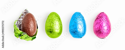 Chocolate easter eggs wrapped in colorful foil, one unwrapped, arranged in a clean horizontal row isolated on white background