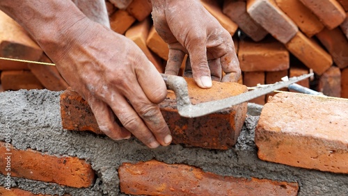 Slika na platnu Close-up of skilled bricklayer working on construction site laying bricks for wa
