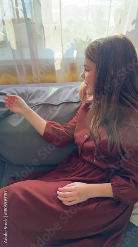 Happy young woman happily playing with miniature pinscher dog on sofa in room