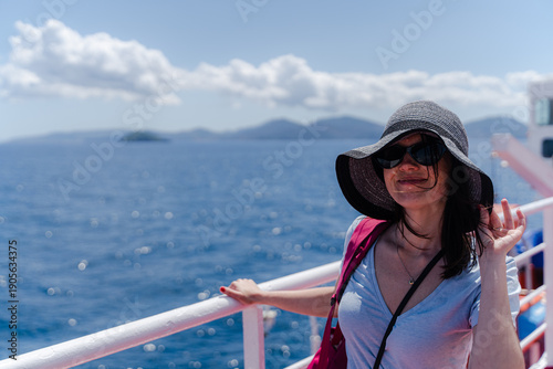 Woman smiling on ferry deck with sea background during travel.