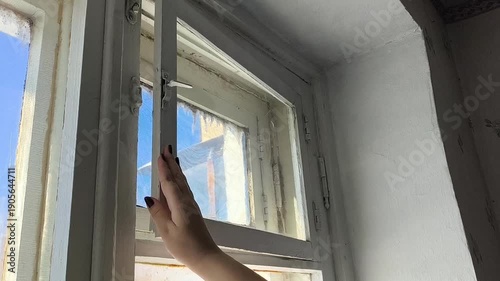 A woman's hand closes the window of an old wooden window in the room. The concept of ventilation of a room. Fresh air