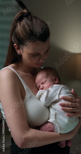 Young mother tenderly cradles her sleeping infant in her arms, creating a peaceful and loving moment indoors