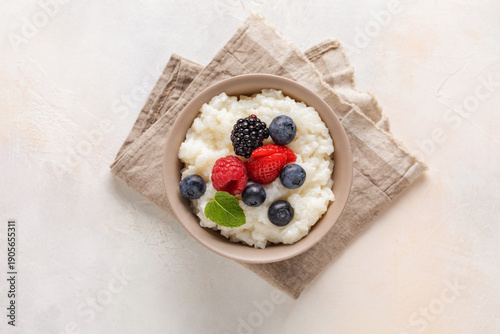 Rice milk porridge in with berries in a bowl on the table. Healthy breakfast. Top view