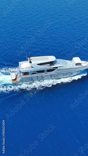 Luxury motor yacht cruising on deep blue ocean water with white foam wake