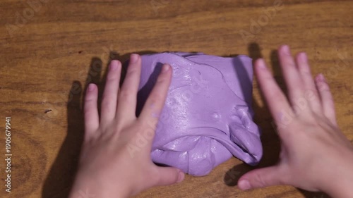Young hands joyfully stretch and squish vibrant purple slime, providing a satisfying sensory and tactile experience.