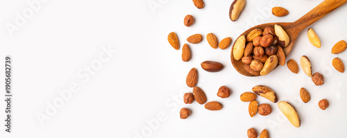 Fotografía Various nuts: almonds, hazelnuts and brazil nuts in wooden spoon on white background top view