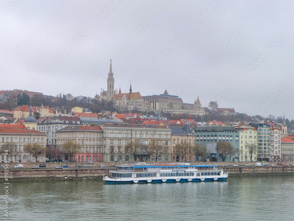 Obraz premium View of Buda and Pest district and boats from Szechenyi bridge, the chain bridge connecting Buda and pest over the Danube river, Budapest, Hungary 