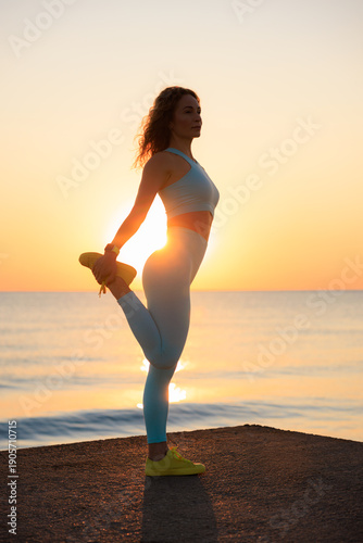 Sporty young woman is stretching against sea background during her vacation. Freedom and summer sport concept