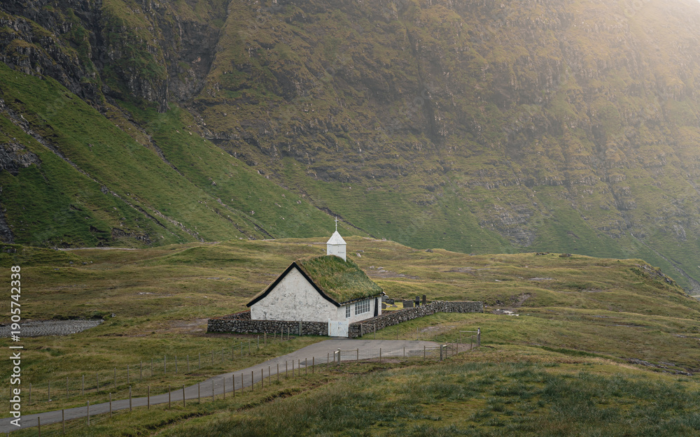 Obraz premium View of traditional nordic church with grass roof in Saksun, Faroe Islands with mountains in background