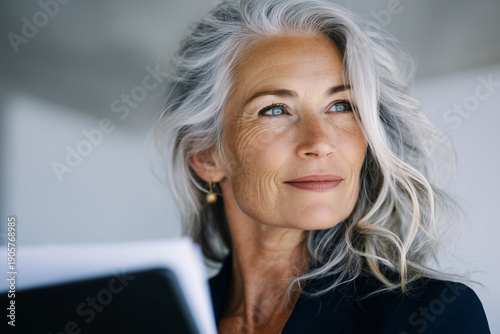 Portrait of a woman in her 70s with elegant gray hair, working in an office