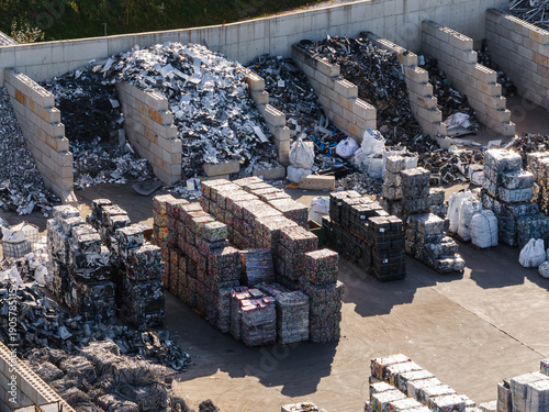 Drone view of scrap metal recycling facility showing sorted piles of metal waste and storage areas during daylight hours.