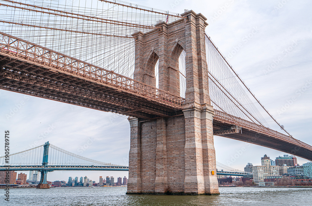 Obraz premium The scenic views of the Brooklyn Bridge, which is a cable-stayed suspension bridge in New York City, spanning the East River between the boroughs of Manhattan and Brooklyn.