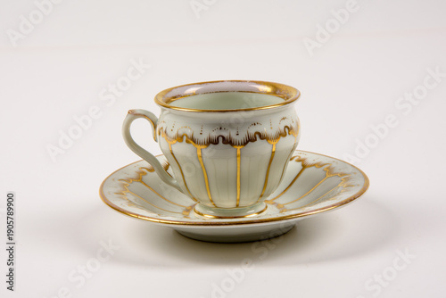 A ceramic tea cup sits on a matching saucer. The cup has a decorative design with gold accents. This scene shows the cup and saucer against a plain white background
