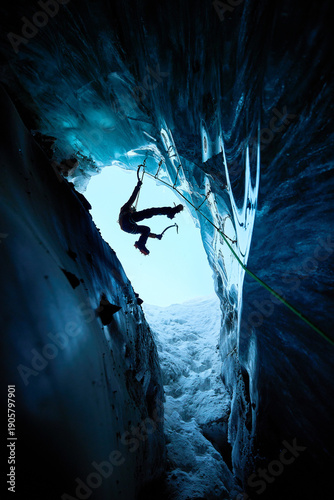 Man climbing frozen ice cave in winter mountains