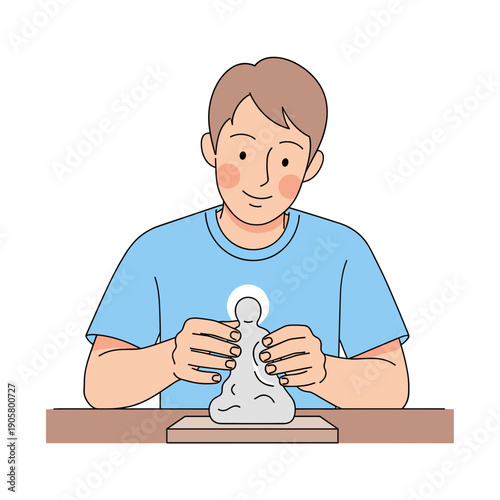 Young man molding figurine from clay while sitting at a table  