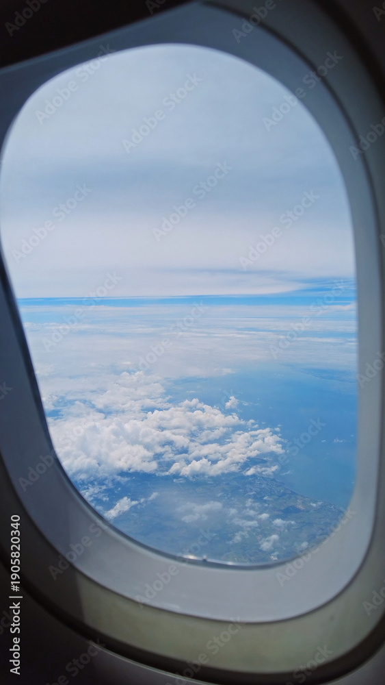 Fototapeta premium View from airplane window showing wing over clouds