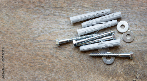 Obraz na plátně Plastic dowels and metal bolts laid out on a wooden surface, copy space