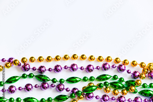 Mardi Gras background. Gold, green and purple beads on white background. Fat Tuesday symbol.