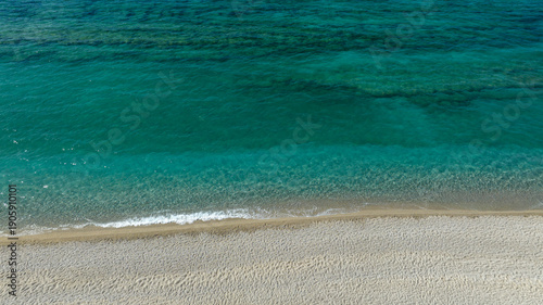 Bilde på lerret Close-up aerial shot of a pristine shoreline where crystal-clear turquoise water gently laps onto pale, fine sand