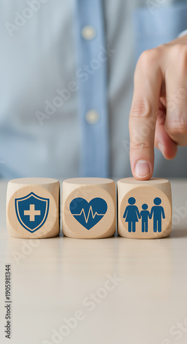 Hand pointing to wooden blocks with shield, heartbeat, and family icons, symbolizing comprehensive health, life, and family insurance protection