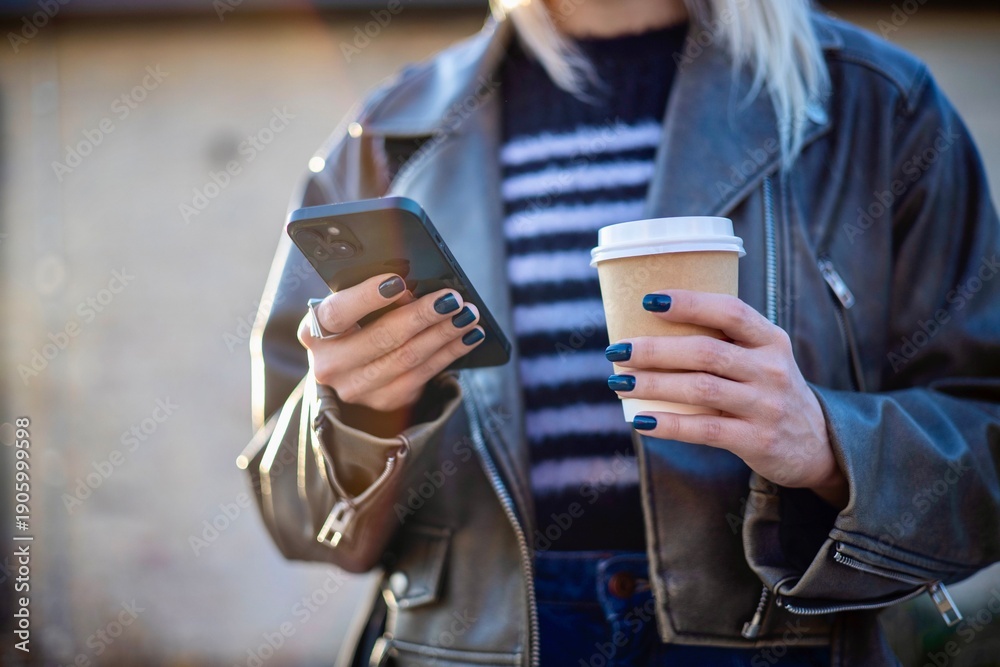 Fototapeta premium Young Woman Using Smartphone While Holding Coffee
