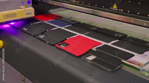 High-speed industrial UV printer simultaneously printing vibrant, high-quality custom graphics onto ten smartphone cases. Precision inkjet technology for bulk mobile accessory manufacturing.