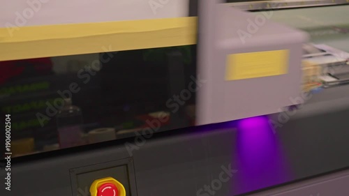 4K footage of a UV printer simultaneously printing an image on ten mobile phone cases. High-tech digital printing process in factory or studio environment, showing precision and automation.