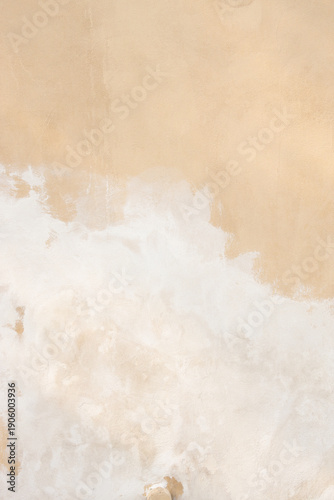 Textured wall surface with beige and white plaster showing signs of wear and aging, creating a rustic and natural appearance suitable for backgrounds and design projects