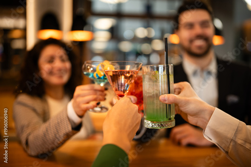 Принти на полотні Friends toasting with colorful cocktails at a bar