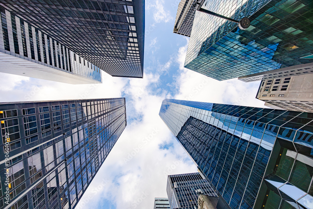 Fototapeta premium Low angle view of modern skyscrapers in New York City forming symmetrical urban canyon against blue sky in Manhattan business district