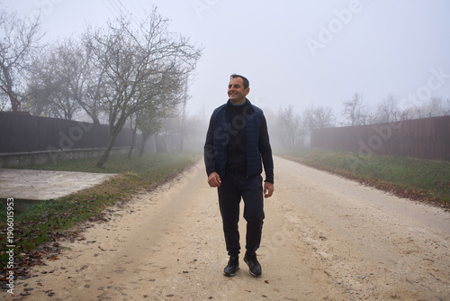 Cuadro en lienzo Man walking on foggy village road