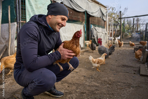 Farmer holding chicken in backyard coop