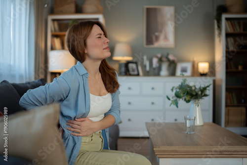 Woman suffering from acute back and abdominal pain at home