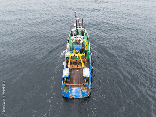 Obraz na plátně Top down aerial view of a commercial fishing trawler with nets deployed in the g