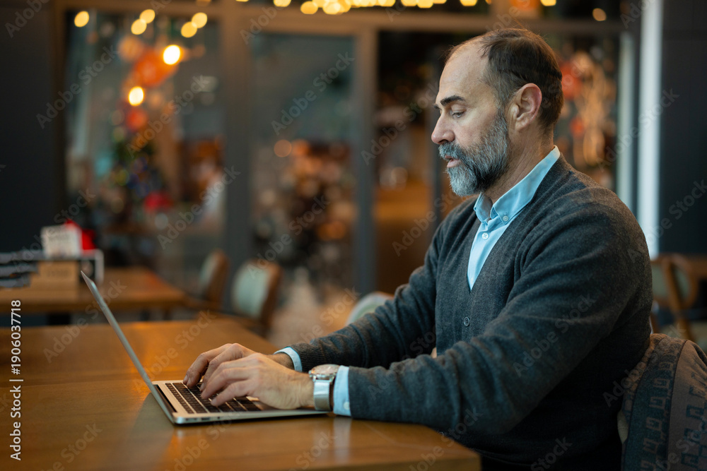 Fototapeta premium Mature man working on laptop in cafe