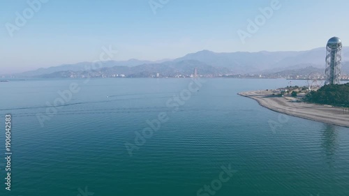 Drone panorama of Batumi coastline with Alphabet Tower and Ferris wheel at sunset. Warm autumn 4K aerial footage, editorial use.