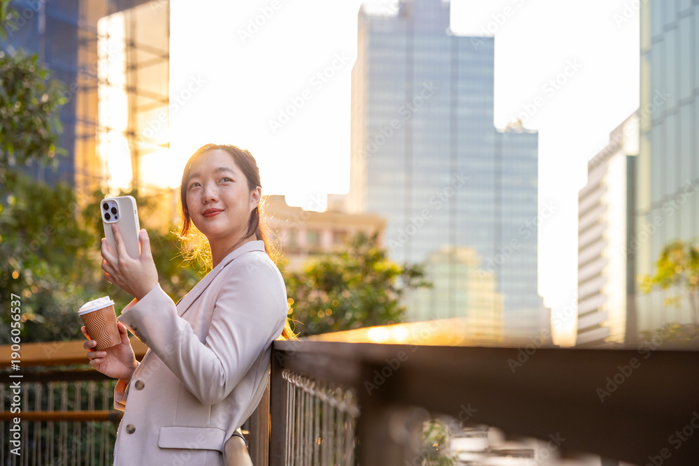 Fototapeta premium Luxury young Asian CEO woman entrepreneur using mobile phone while walking in the urban skyscraper street modern office downtown on background for business communication and urban lifestyle