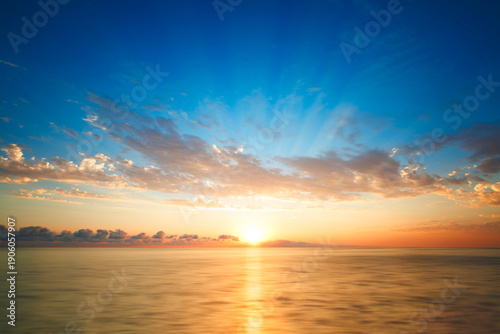 Bright beautiful orange sunset on the beach and by the sea, smooth sea, sunny path in the sea, sun on the sea horizon, sun rays in the blue sky - Vintage filter