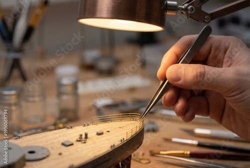 Hobbyist using precision tweezers to assemble a detailed wooden model of a historic ship.