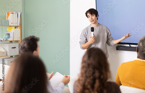 Fotografie Portrait of young male teacher lecturing to professionals during training meetin