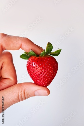Hand holding ripe red strawberry 