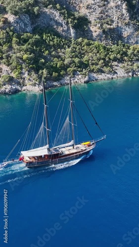 Wallpaper Mural Traditional wooden gulet sailing on a bright blue sea near a lush green coastline Torontodigital.ca