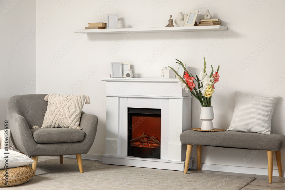 Naklejka premium Interior of living room with fireplace, armchair and gladiolus flowers