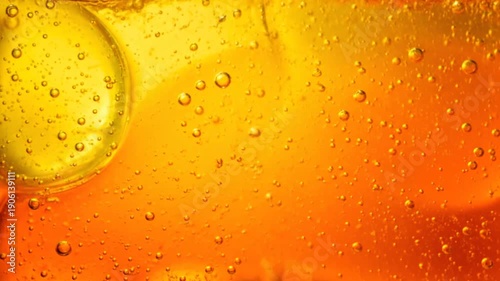 Macro closeup of fresh water drops and golden bubbles on a wet orange background creating an abstract liquid texture of cold beer foam