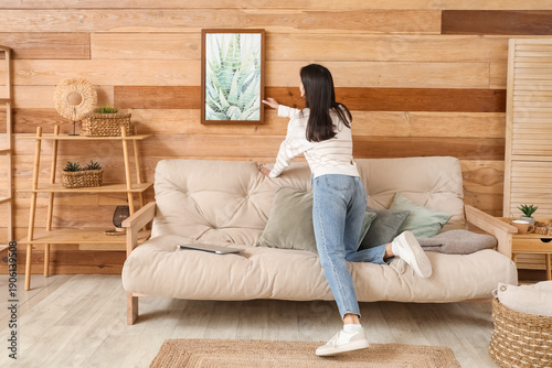 Young woman hanging picture...
