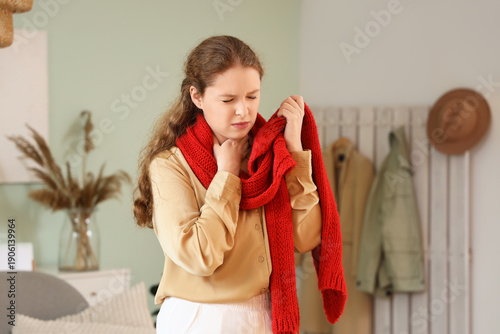 Quadro em tela Sick young woman with sore throat and scarf at home
